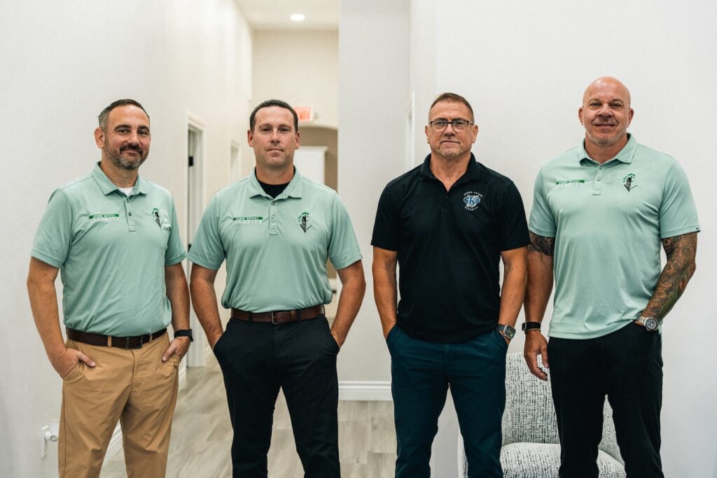 Green Knight Security leadership team standing in office hallway, four men in branded polos